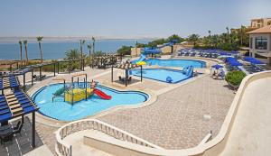 a resort with two pools with slides and chairs at Dead Sea Spa Hotel in Sowayma