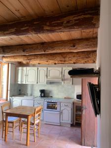 Una cocina con gabinetes blancos y una mesa de madera. en LA PATISSERIE, en Saint-Sauveur-de-Cruzières