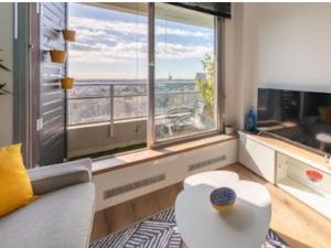 een woonkamer met een tafel en een groot raam bij Cocon design et cosy à La Défense, vue imprenable sur Paris in Puteaux