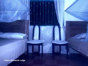 two chairs in a room with a bed and two beds at Cabaña RECUERDO Lodge, B & B in Moñitos