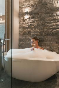 a woman sitting in a bath tub with a glass of wine at Alpinhotel Berghaus spa in Tux