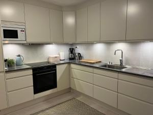 a kitchen with white cabinets and a sink and a microwave at Rom til leie i Tromsø - nært alt - flott standard in Tromsø +22 photos