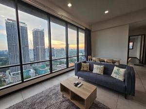 a living room with a blue couch and large windows at Opus Residences by Star Haven in Kuala Lumpur