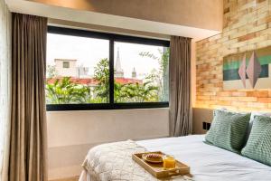 a bedroom with a bed and a large window at Caliza Roma Residences by Tasman in Mexico City
