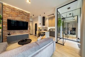 a living room with a couch and a brick wall at BalticSky Loft Premium, Apartament Kołobrzeg, Basen, Jacuzzi, Sauna in Kołobrzeg