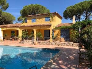 a villa with a swimming pool in front of a house at Sous les pins parasols in Vidauban