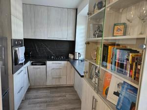 a kitchen with wooden cabinets and bookshelves at Draugyste Apartment in Šiauliai
