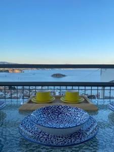 a table with two plates and two cups on a balcony at Daphne Bungalows in Tolo