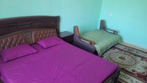 Un dormitorio con una cama con sábanas y almohadas púrpuras. en Уютная квартира в Бухаре со всеми удобствами, en Bukhara