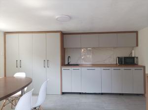 a kitchen with white cabinets and a table at Casa Jisa in Turda