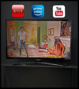 een televisie met een man en een vrouw op een bed bij Prático Viena - Free Parking - 24 hour doorman in Parque Industrial +21 foto's