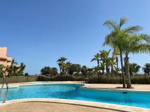 a swimming pool with palm trees in a resort at Casa Paradise 2, Ground Floor Apartment on Mar Menor Golf Resort in Torre-Pacheco