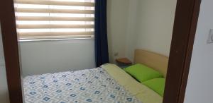 a bedroom with a bed with green pillows and a window at city center apartment 1 in Niš