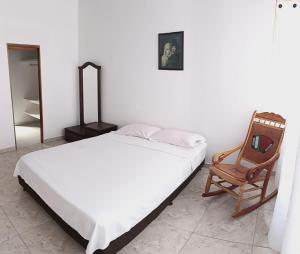 a bedroom with a bed and a wooden chair at Comodas y agradables Habitaciones en Chipre in Manizales