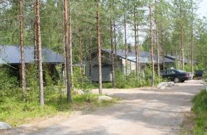 una casa en el bosque con un coche aparcado delante en Haarusmaa Holiday Apartments Kauhava, en Härmä