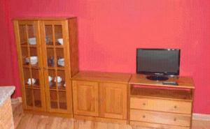 a red room with a tv on a wooden entertainment center at Alojamiento rural la Bellosina in Cabezabellosa
