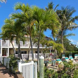 a house with palm trees and a white fence at Tortuga Inn Beach Resort Unit #229 in Bradenton Beach