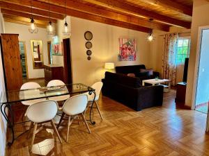 Una sala de estar con una mesa de cristal y sillas blancas. en Casa Vista Teide con Jardín, Barbacoa y Fuente Zen, en Icod de los Vinos