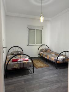 two twin beds in a room with a window at Appartement à louer Complexe City Center in Oued Laou +17 photos