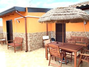 a patio with a table and chairs and a straw umbrella at Al chiaro di luna in Catania