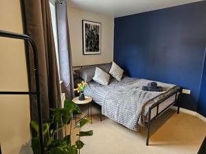 Un dormitorio con una cama con una pared azul. en 2 bedroom spacious flat, en Gloucester