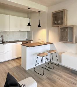 a kitchen with white cabinets and a counter and stools at Par71 - Marco Simone golf club Rome in Marco Simone +32 photos