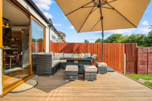 un patio con sofá y sombrilla en Casa Marina- 4 bedroom house with garden and balcony, en Golders Green