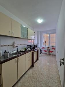une grande cuisine avec des armoires blanches et une table dans l'établissement Happy Yonder - Piața Romană - lângă metrou, à Bucarest