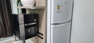 a refrigerator and a microwave next to a wall at Lagoa Quente Flat in Caldas Novas
