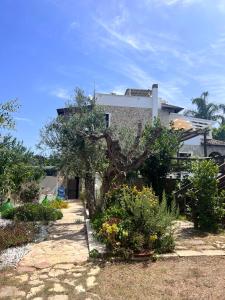 a house with a tree in a yard with flowers at Villa Casa Vacanze Fiore in Gallipoli