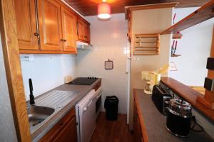 a small kitchen with wooden cabinets and a sink at Résidence Roches Rouges A - Appartement calme et près des pistes. MAE-2474 in Tignes