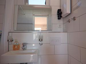 a white bathroom with a sink and a mirror at Strandhaus an der Wohlenberger Wiek in Hohenkirchen +31 photos