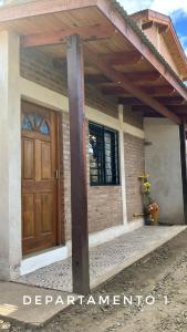 a house with a wooden door and a porch at La Maga in Santa Rosa de Calamuchita
