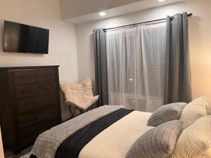 ein Schlafzimmer mit einem Bett, einer Kommode und einem Fernseher in der Unterkunft The Retreat in Lakewood