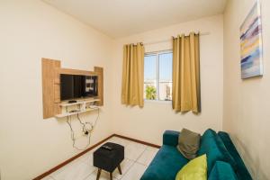 a living room with a blue couch and a tv at Rental São José - Acomodações Residenciais II in São José