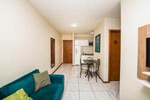 a living room with a blue couch and a kitchen at Rental São José - Acomodações Residenciais II in São José