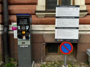 eine Parkuhr mit einem Schild neben einem Gebäude in der Unterkunft 1BR Demure Design Urban Living Space in Helsinki