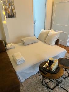 Una gran cama blanca con una mesa con velas encima. en Spacieux Appartement Persan, en Persan