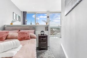 ein Schlafzimmer mit einem Bett mit rosa Kissen und einem Fenster in der Unterkunft 2-Bed Studio At The Heart of Birmingham City Center in Birmingham