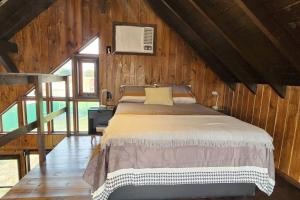 a bedroom with a bed in a wooden room at Recanto AlceNegro in Miguel Pereira