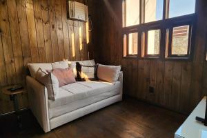 a white couch in a room with wooden walls at Recanto AlceNegro in Miguel Pereira