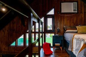 a bedroom with a bed and windows in a cabin at Recanto AlceNegro in Miguel Pereira