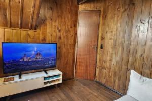 a living room with a flat screen tv on a wooden wall at Recanto AlceNegro in Miguel Pereira