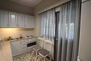 a kitchen with white cabinets and a sink and a window at Lia Beach house near airport in Artemida
