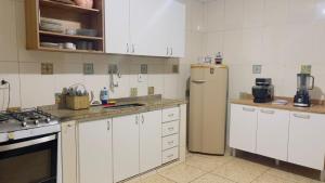 a kitchen with white cabinets and a refrigerator at House Temporada in Búzios +19 photos