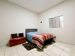 a bedroom with a bed and a red chair at Espaço Sweet próximo ao Aeroporto Guarulhos in Jardim Bela Vista