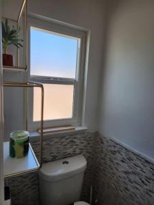 a bathroom with a window and a white toilet at The Coastal Comfort in Oxnard +20 photos
