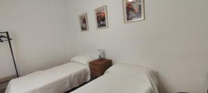 two beds in a white room with pictures on the wall at Los picarzos apartamento in Ayna