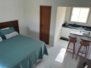 a bedroom with a bed and a kitchen with a sink at Chalé Gameleiras in Monte das Gameleiras