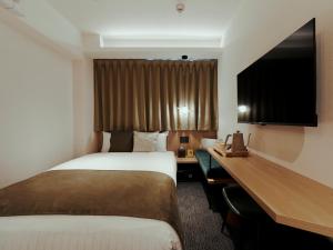 大阪市にあるR Hotel Namba Daikokuchoのベッドと机があるホテルの部屋